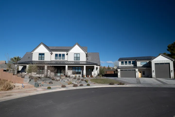 Modern farmhouse-style home featuring a covered front porch with stone accents, dark-framed windows, detached RV garage, ADU, and workshop area.