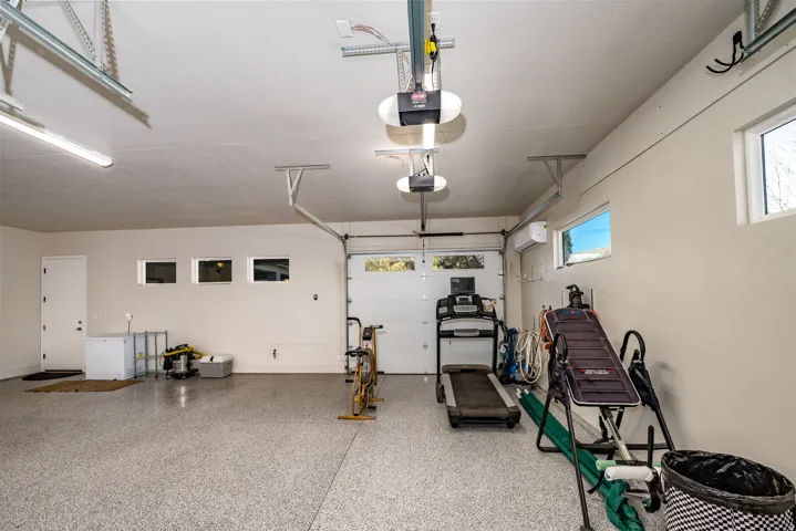 Spacious garage with an epoxy floor, multiple windows providing natural light, and a dedicated side entry door