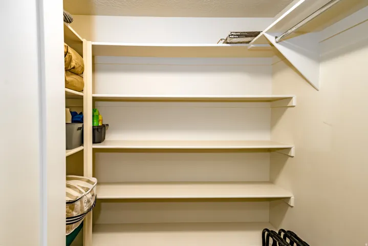 Built-in shelving unit providing ample storage, corner shelving, and a closet rod