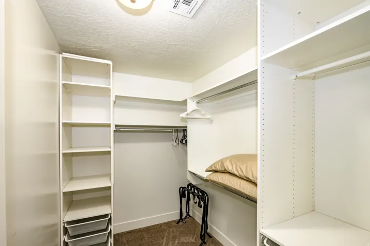 Walk-in closet featuring extensive shelving and hanging storage with white built-in cabinetry, multiple hanging rods for organization, and carpeted flooring