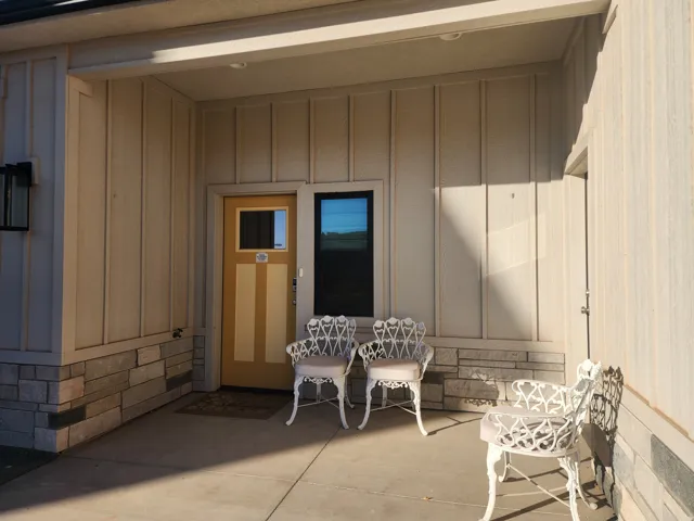 Covered entry featuring a paneled wood door with glass inset, an additional fixed window, vertical siding, and a stone veneer foundation