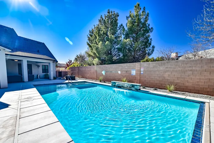 Rectangular swimming pool featuring a tiled waterline, a stone-clad water feature, and surrounding concrete paver decking