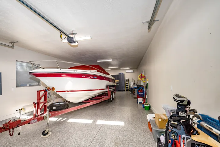 Spacious garage featuring a finished epoxy floor, ample overhead lighting, and dedicated wall-mounted shelving