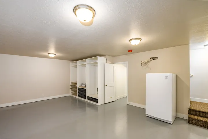 Spacious room featuring light-toned walls and a smooth gray floor