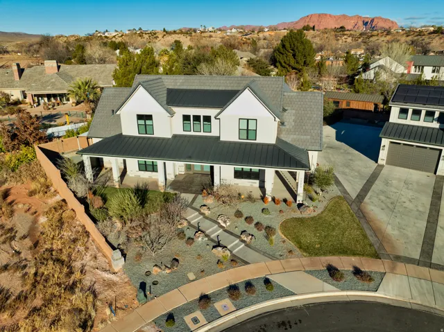 Modern farmhouse exterior featuring an extended covered porch, a two-car garage with an attached structure, and a low-maintenance landscape with a flagstone path