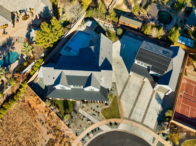 Contemporary residence featuring a multi-gabled roofline, an expansive driveway, a built-in swimming pool, a private tennis court, and an integrated solar panel system