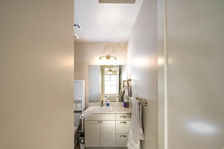 Bathroom featuring a vanity with a rectangular sink, integrated countertop, and brass-finish lighting fixture