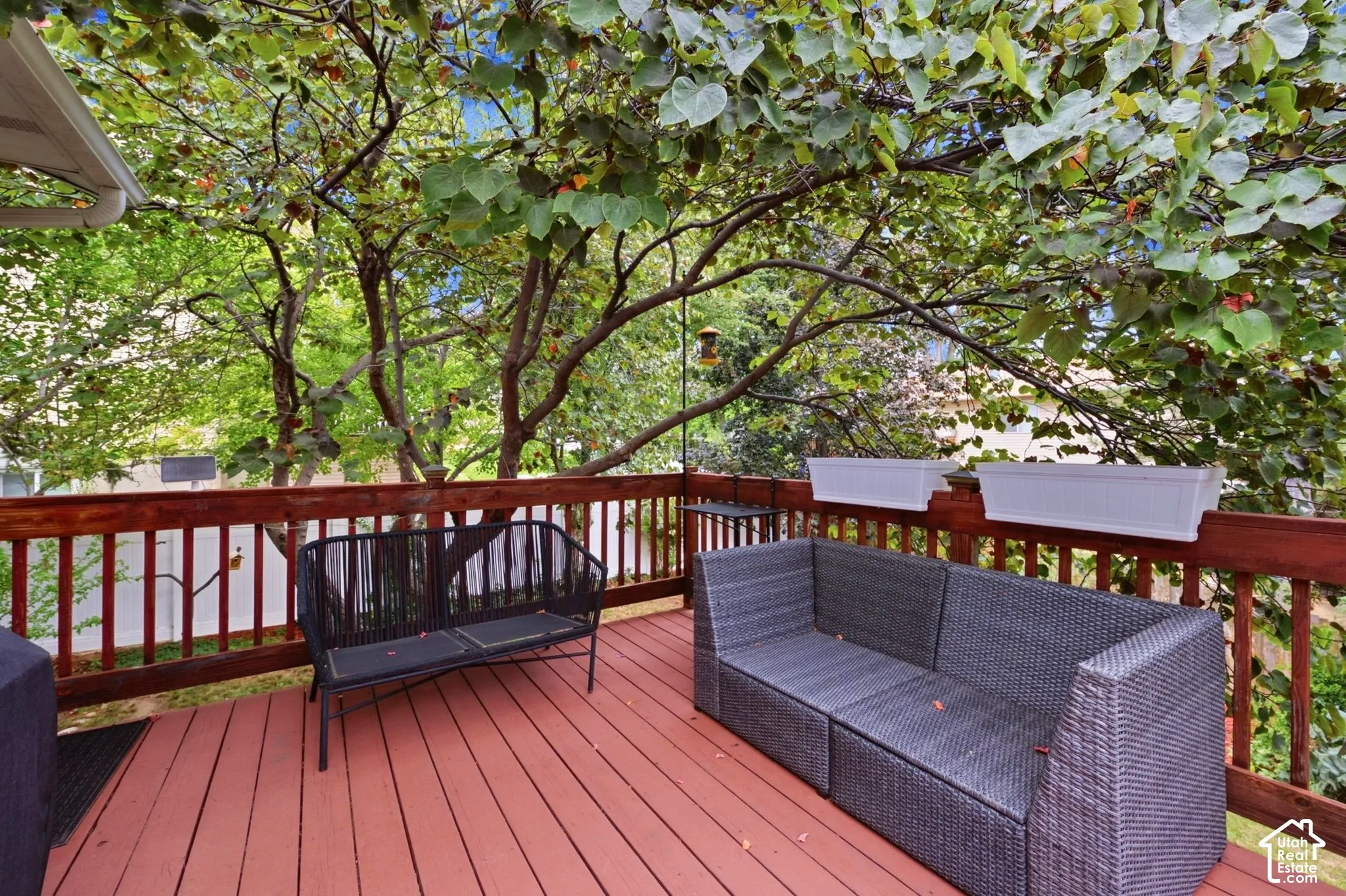 Spacious outdoor deck featuring red-toned wood-finish flooring and matching railings