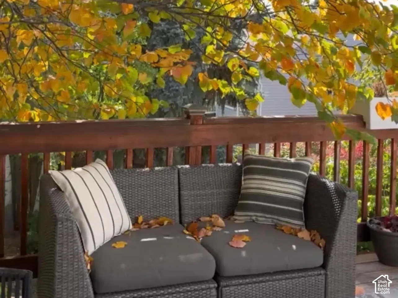 Outdoor deck with wood railing, decorative string lighting, and mature foliage