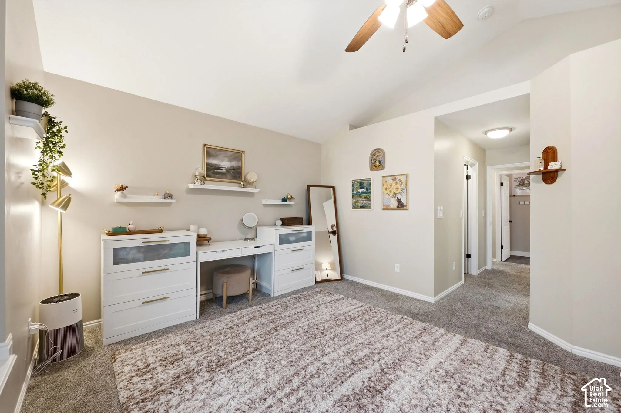 Vaulted ceiling with an overhead fan, plush carpeting, and light neutral wall tones