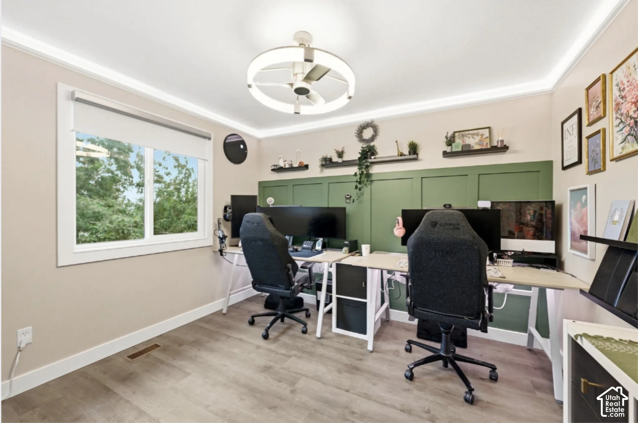 Spacious room featuring wood-finish flooring, a large window, crown molding, and a modern ceiling fan with integrated lighting