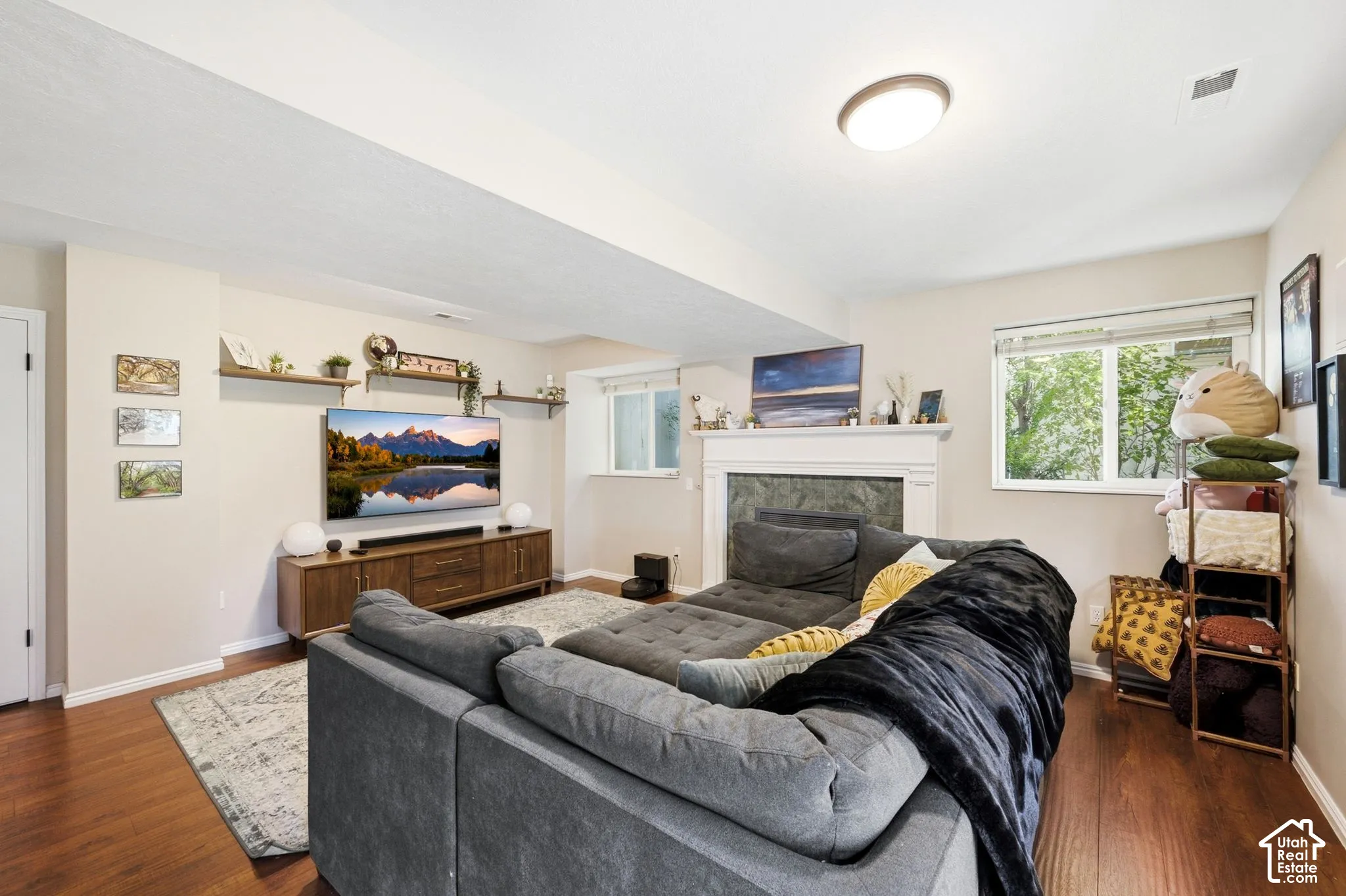 Living area featuring wood-finish flooring, recessed lighting, and a white-mantled fireplace with a stone surround