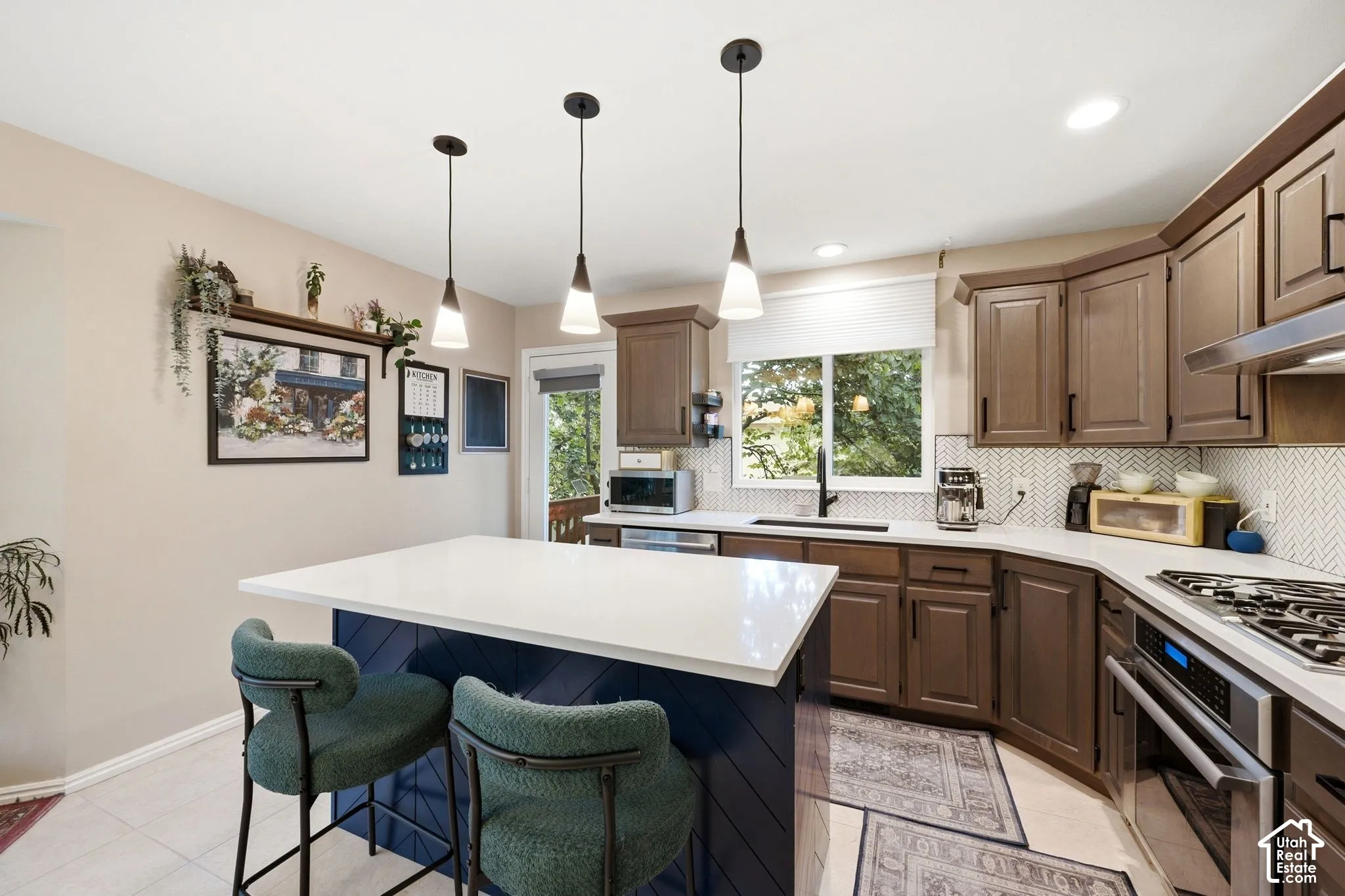 Spacious kitchen featuring a central island with white countertop, dark blue paneling, and three pendant lights
