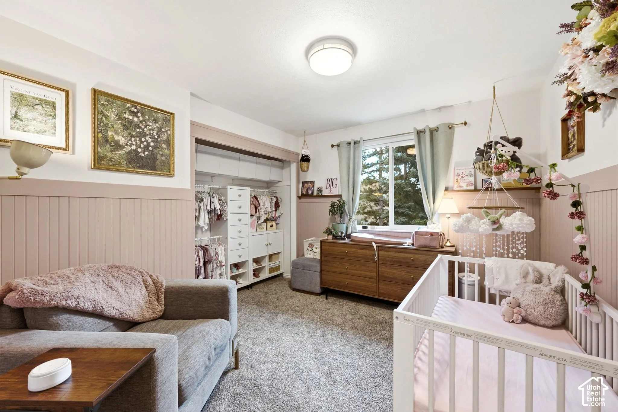 Room featuring light-colored walls with a contrasting wainscoting, an integrated custom closet system, a window with outdoor landscaping, and ceiling-mounted lighting