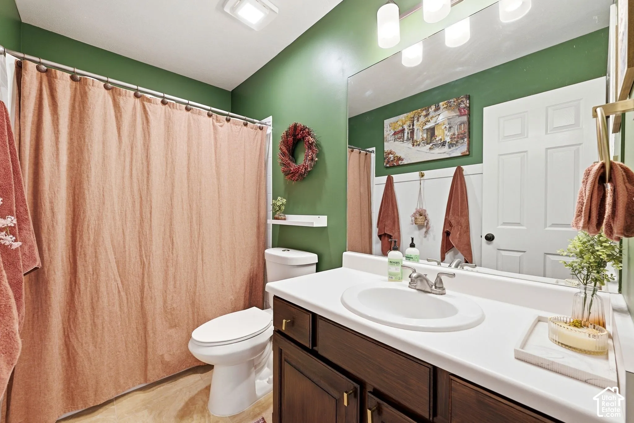 Bathroom featuring a dark wood-finish vanity with a white countertop and integrated sink, a rectangular mirror, a toilet, and a shower area
