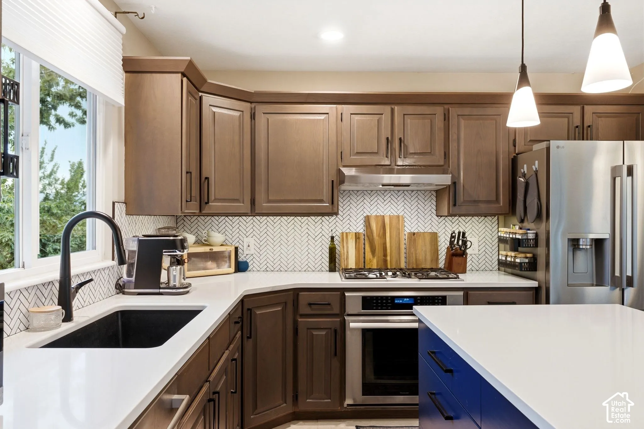 Kitchen featuring dark wood cabinetry, white countertops, and a herringbone-patterned tile backsplash