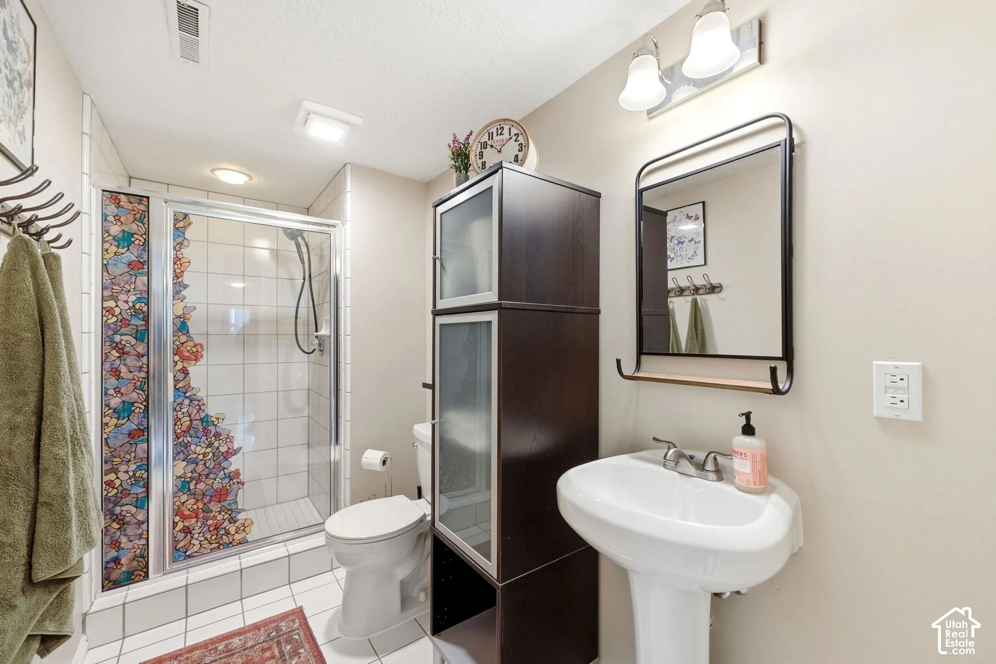 Bathroom featuring a pedestal sink, framed mirror with integrated shelf, and a shower with glass enclosure
