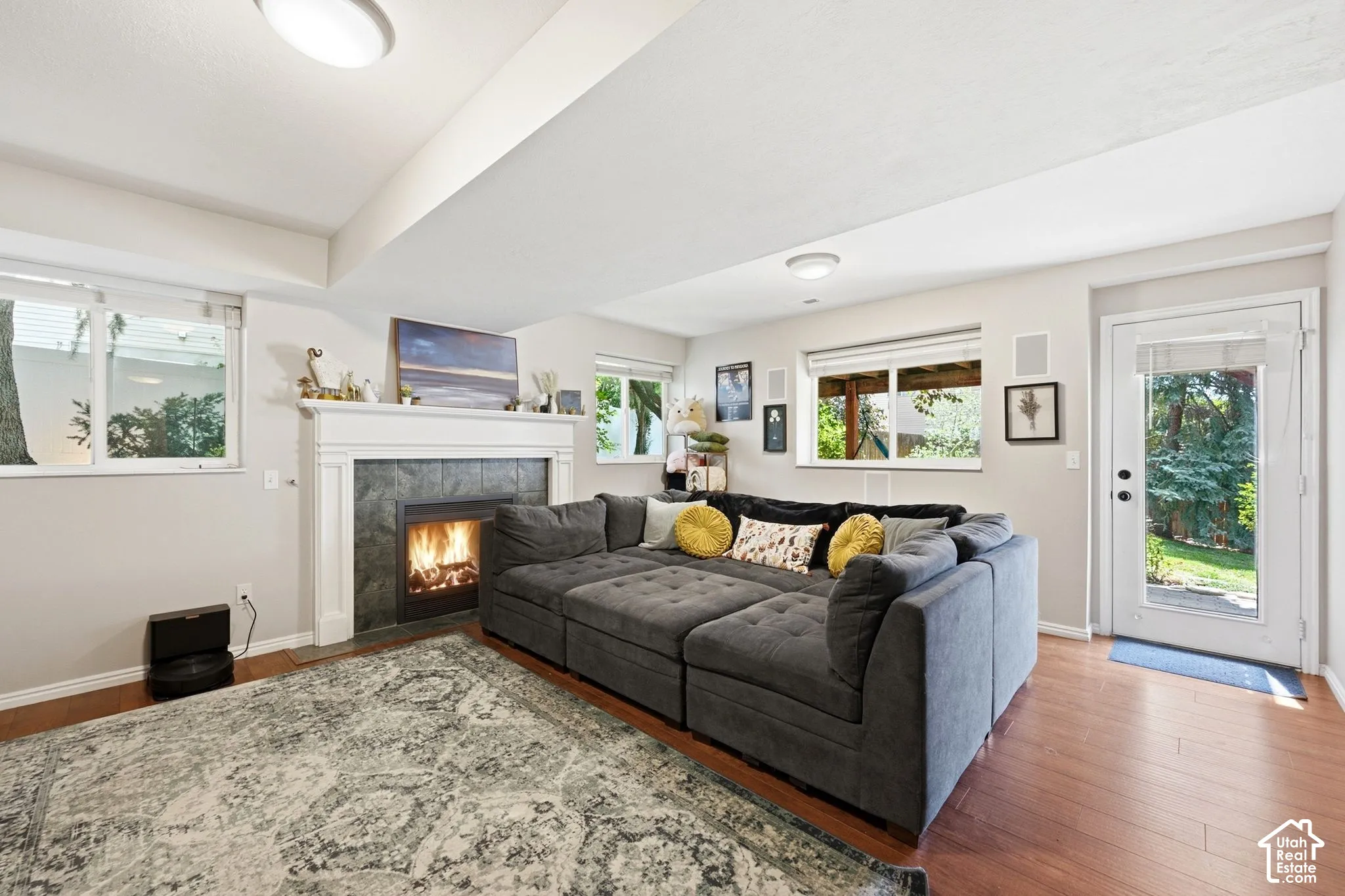 Living area featuring a fireplace with a dark tile surround and white mantel, wood-finish flooring, recessed lighting, and multiple windows