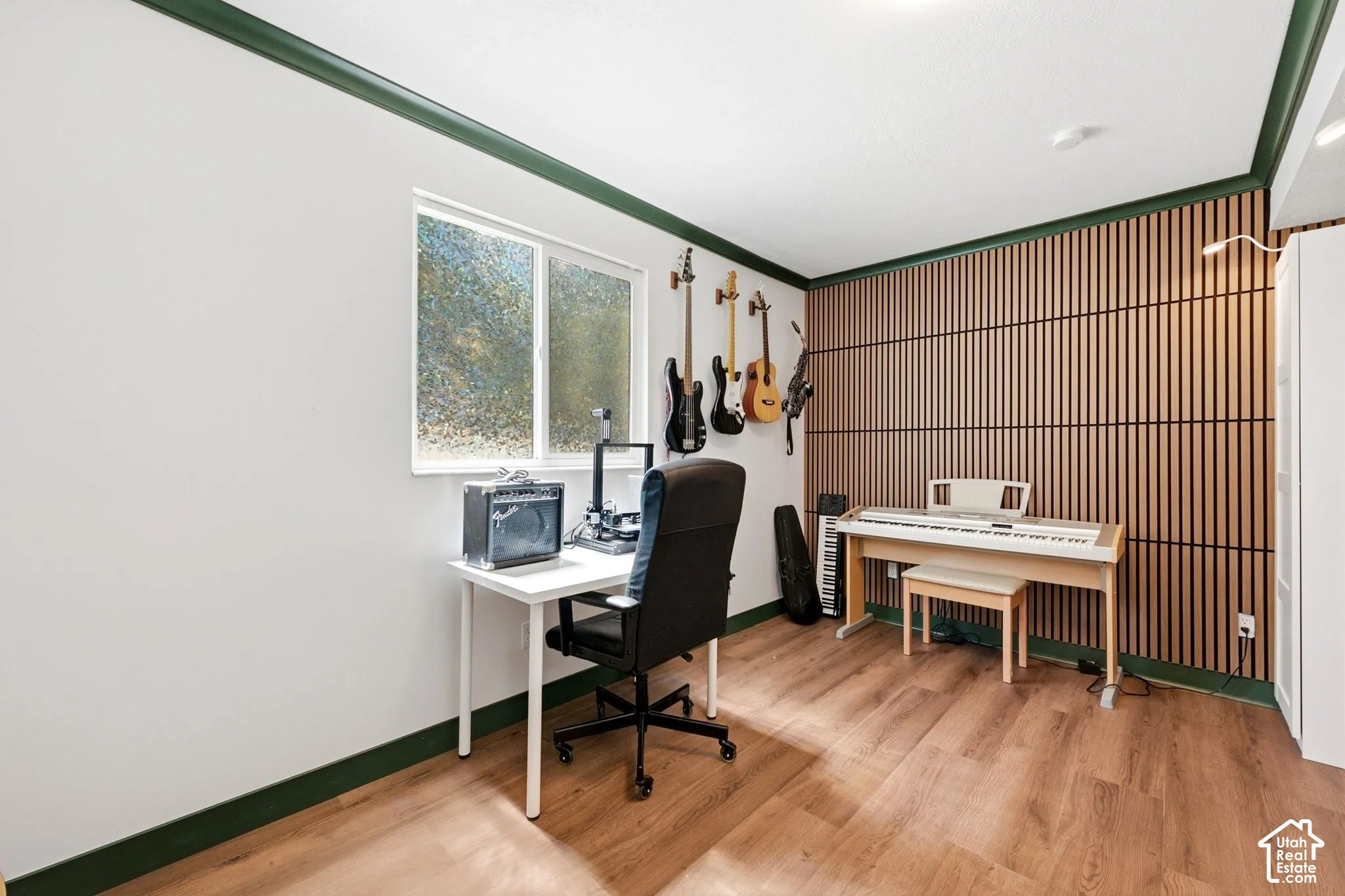 Versatile room featuring wood-finish flooring, a contemporary accent wall with vertical wood slats, and a white-framed window