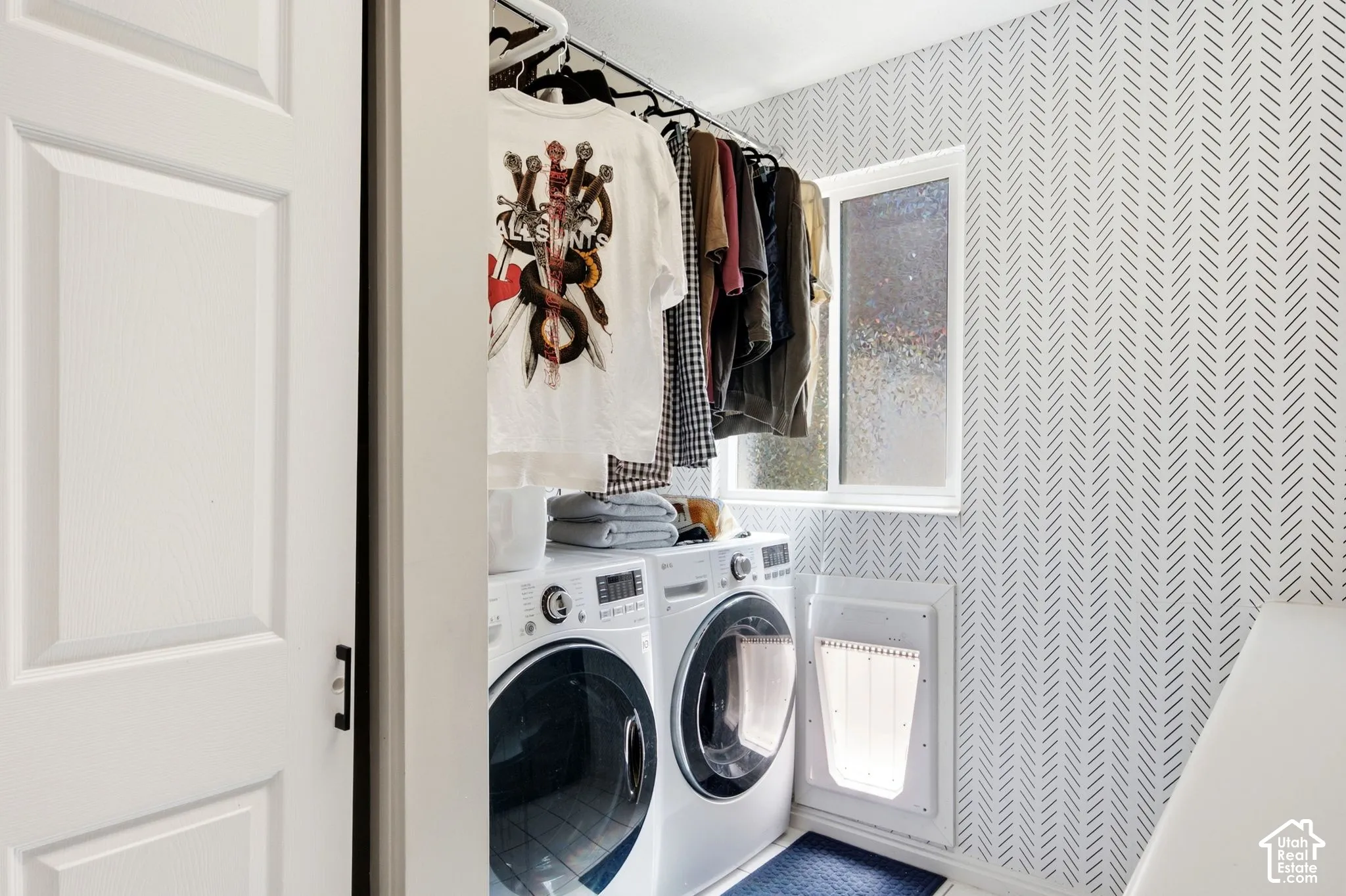 Dedicated laundry area featuring front-loading washer and dryer units, a wall-mounted clothing rod, and a window for natural light