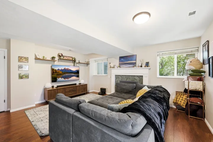 Living area featuring wood-finish flooring, recessed lighting, and a white-mantled fireplace with a stone surround