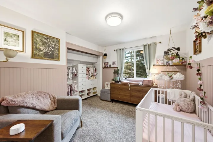 Room featuring light-colored walls with a contrasting wainscoting, an integrated custom closet system, a window with outdoor landscaping, and ceiling-mounted lighting
