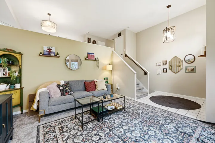 Spacious living area featuring a vaulted ceiling and a partial wall overlooking another space