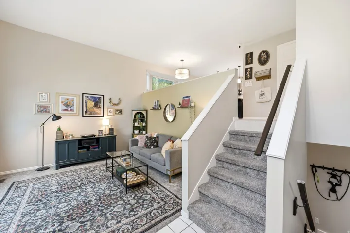 Living area featuring neutral wall tones, a high ceiling, and a partial wall dividing the space