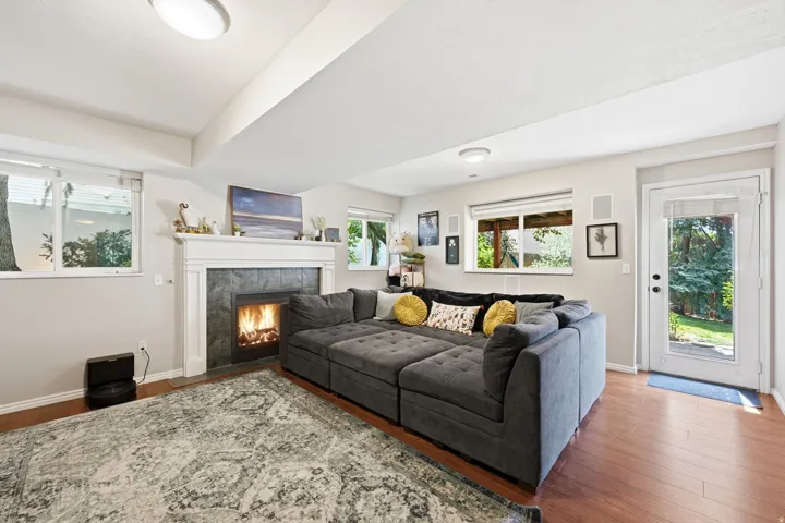 Living area featuring a fireplace with a dark tile surround and white mantel, wood-finish flooring, recessed lighting, and multiple windows