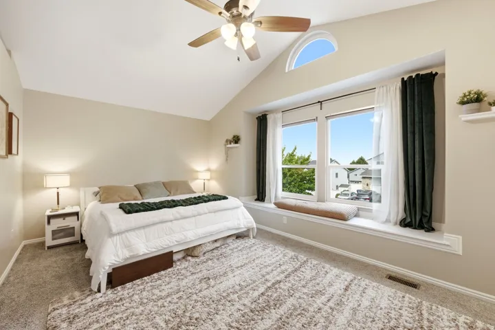 Vaulted ceiling room featuring a large window with an arched transom, a built-in window seat, and neutral-toned carpeting