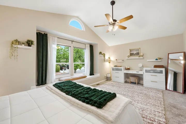 Vaulted ceiling with ceiling fan, large bay window with window seat, and an arched transom window