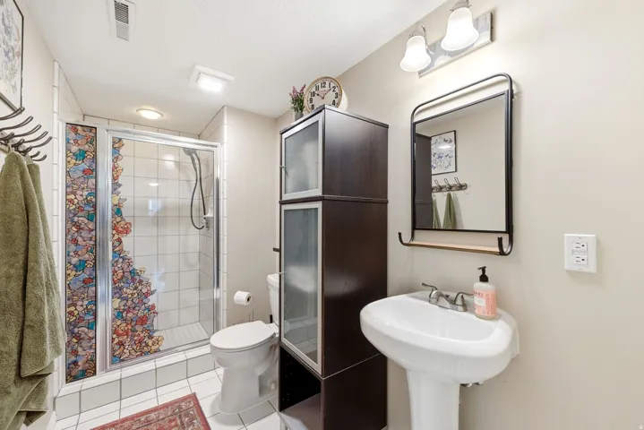Bathroom featuring a pedestal sink, framed mirror with integrated shelf, and a shower with glass enclosure