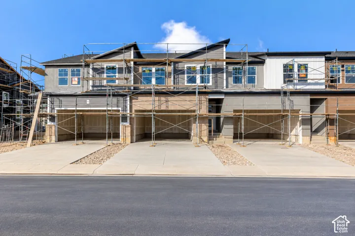 Multi-unit exterior featuring mixed-material siding, gabled rooflines, double-pane windows, and attached garages with concrete driveways