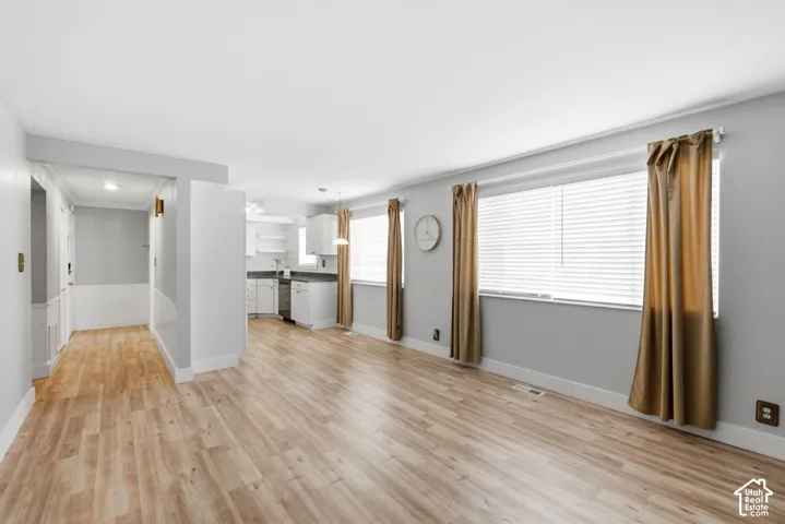 Open-concept living area with wood-finish flooring, neutral wall tones, and ample light from the two large windows.