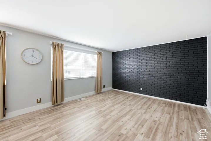 Large living area with neutral flooring and solid brick accent wall.
