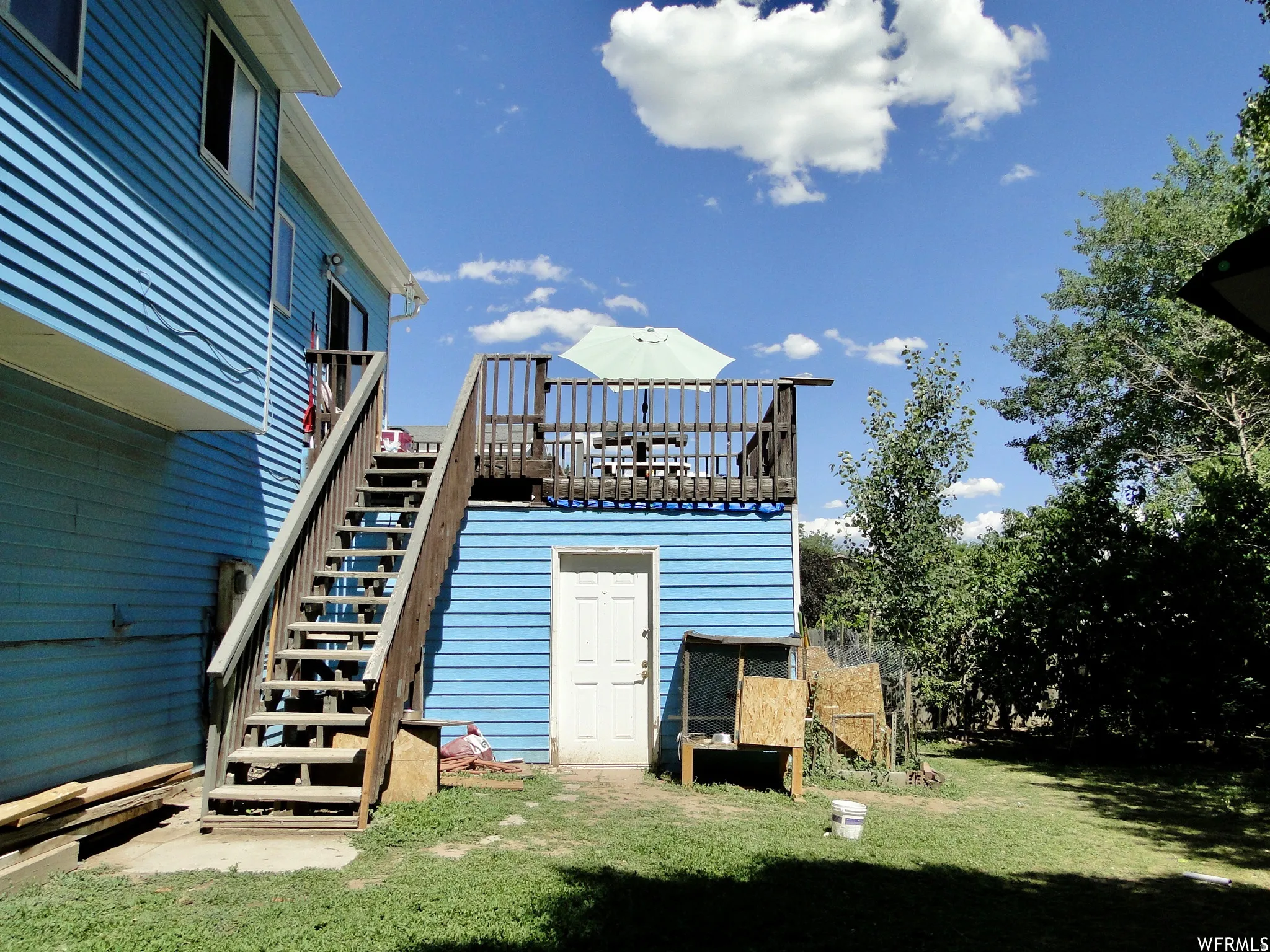 Upper-level deck with wood railing, accessed by exterior wood stairs