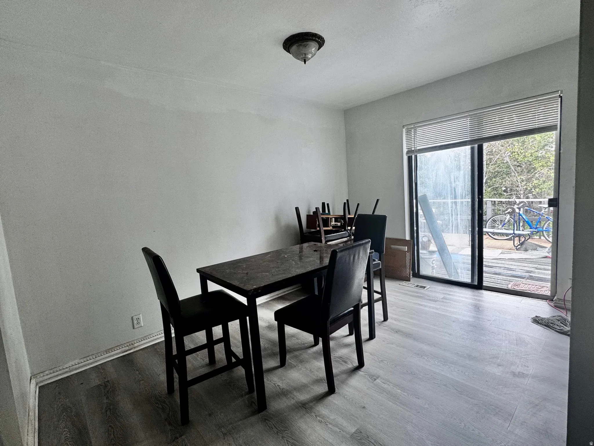Spacious room featuring wood-finish flooring, a contemporary ceiling light fixture, and large sliding glass doors providing outdoor access