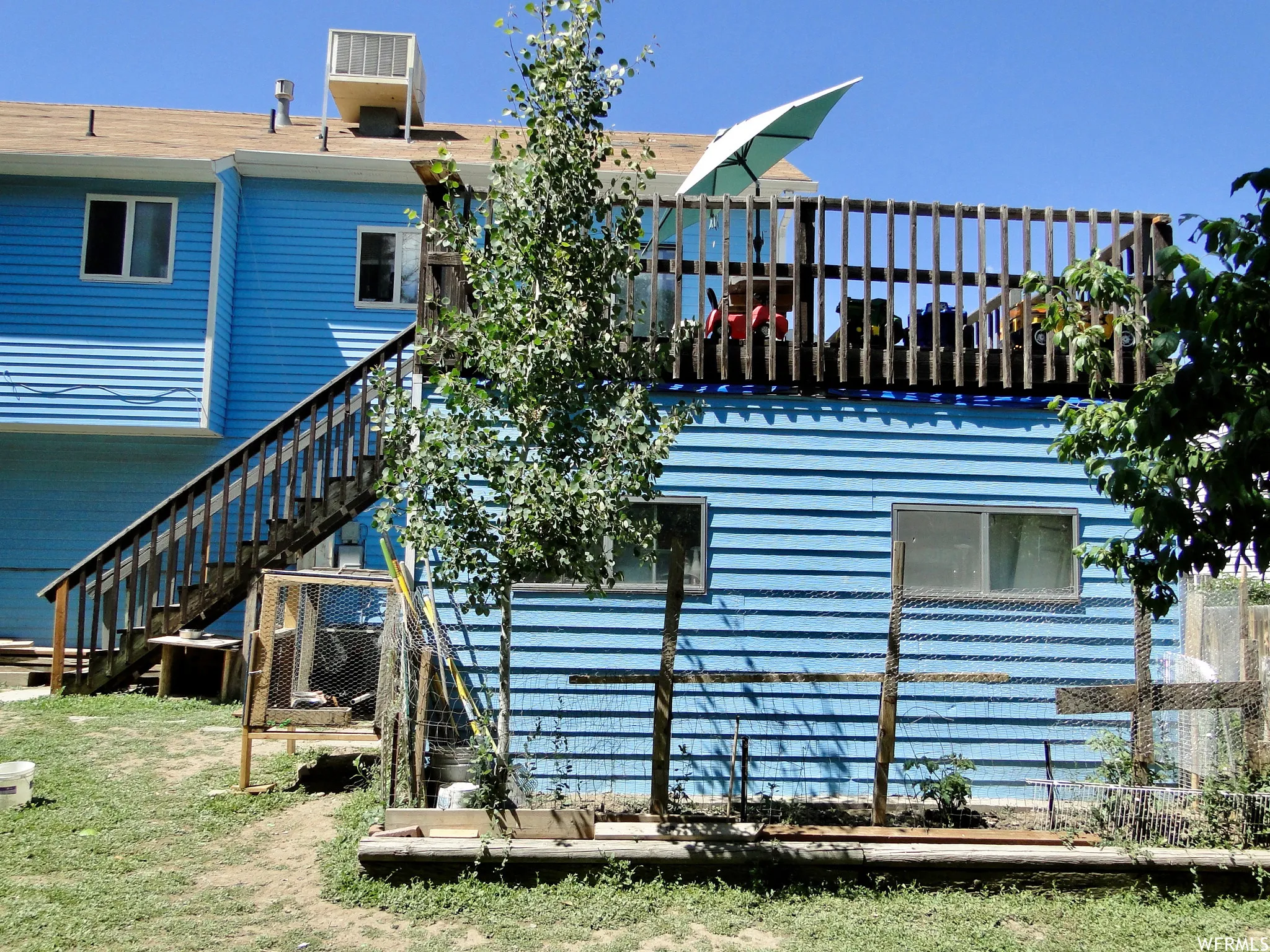 Exterior showcasing blue horizontal siding, a second-story wood deck with railings, and an exterior staircase