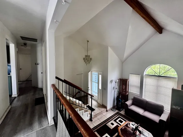 Entry foyer featuring a vaulted ceiling with exposed wood beam, a crystal chandelier, and tiled flooring