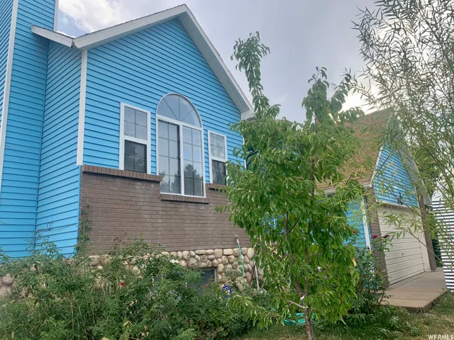 Property exterior featuring blue siding, a brick facade, and a stone foundation