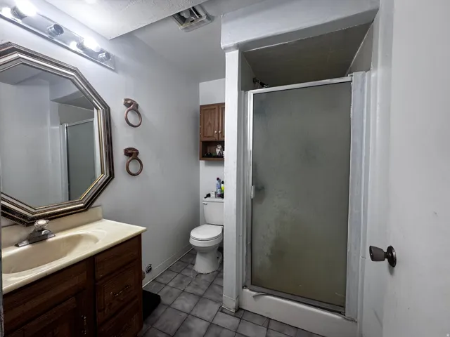 Bathroom featuring a wood-finish vanity with an integrated sink and an octagonal framed mirror