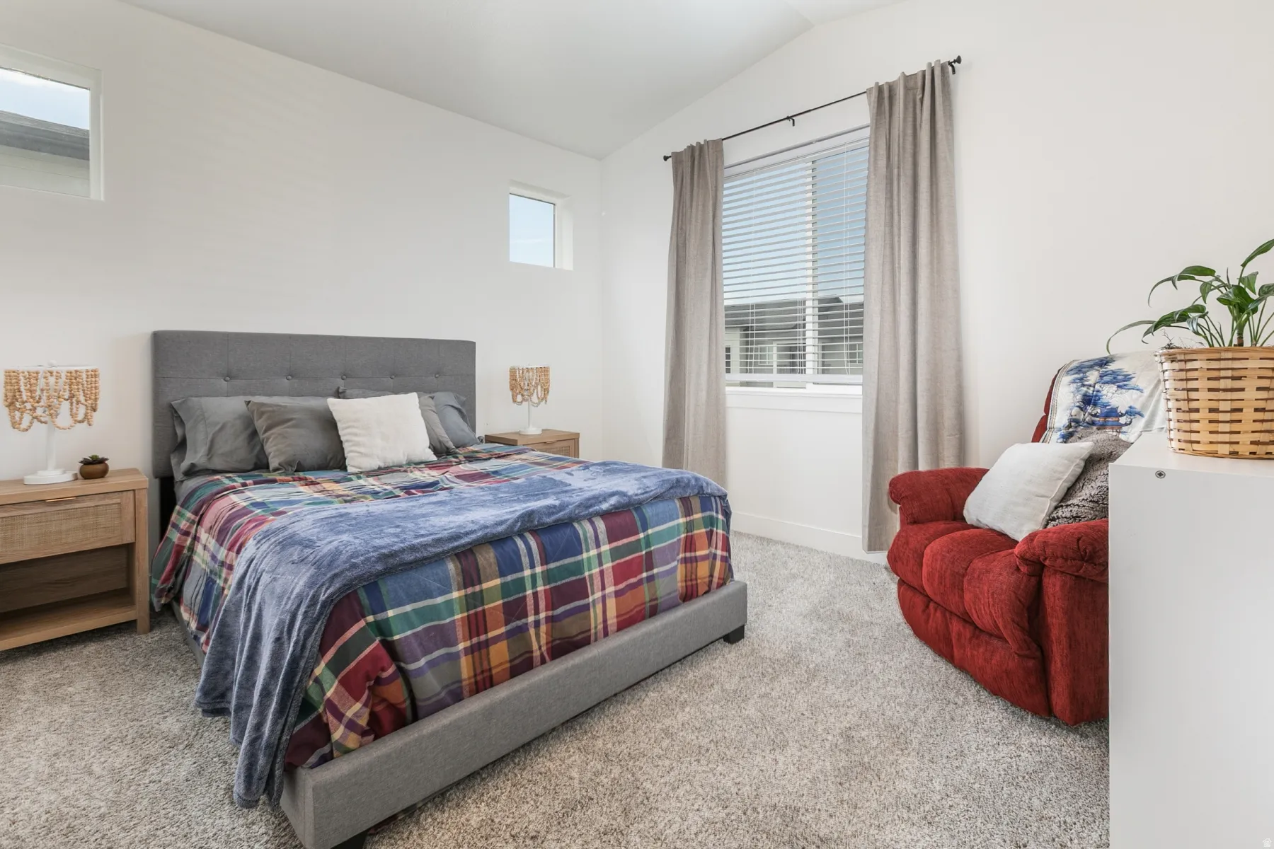 Bright bedroom featuring a vaulted ceiling and light gray carpeting
