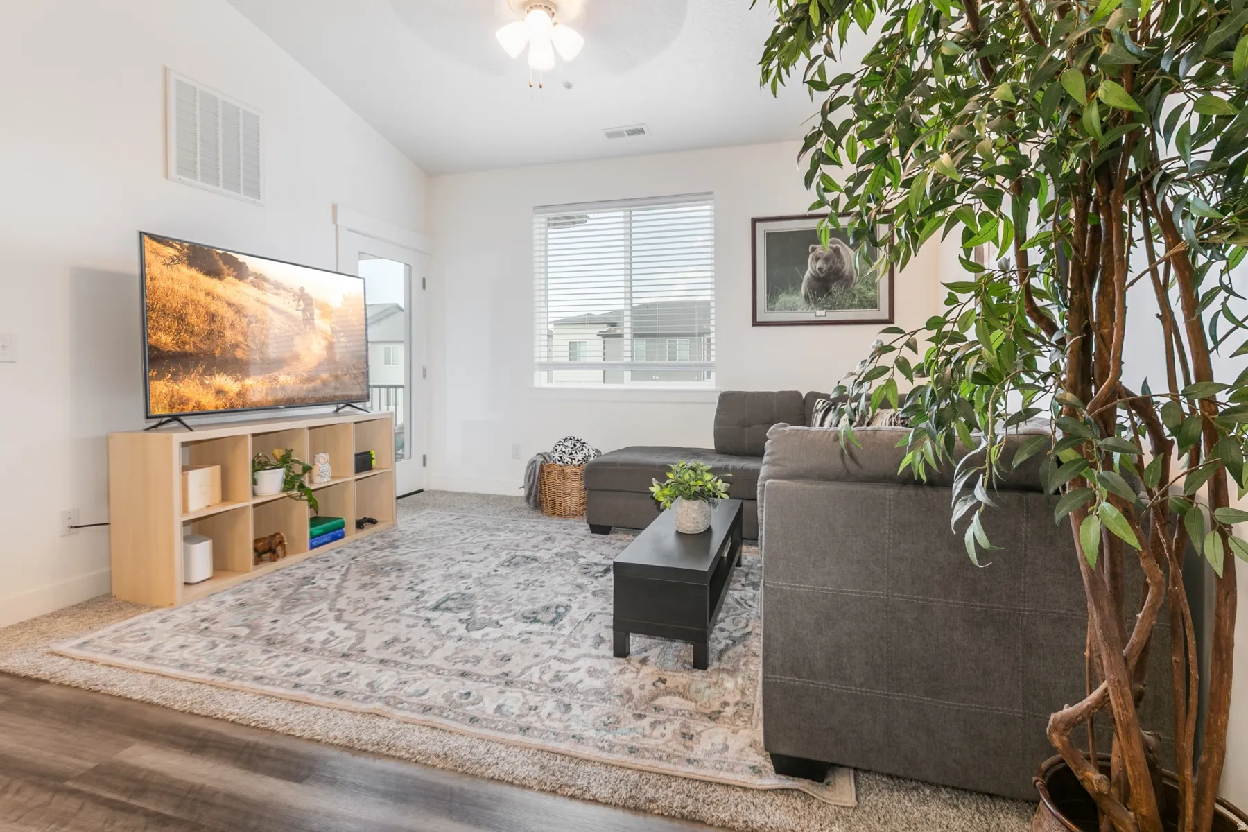 Living area featuring a vaulted ceiling, wood-finish flooring, and a glass-paneled exterior door