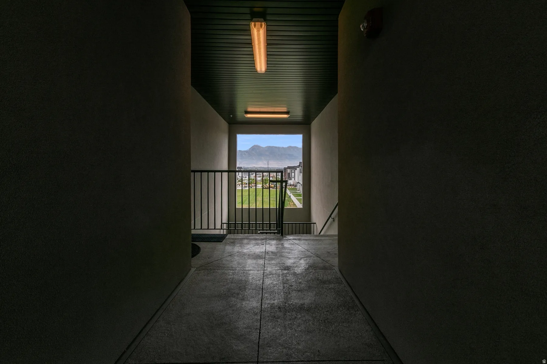 Concrete walkway with a metal railing and mountain scenery beyond