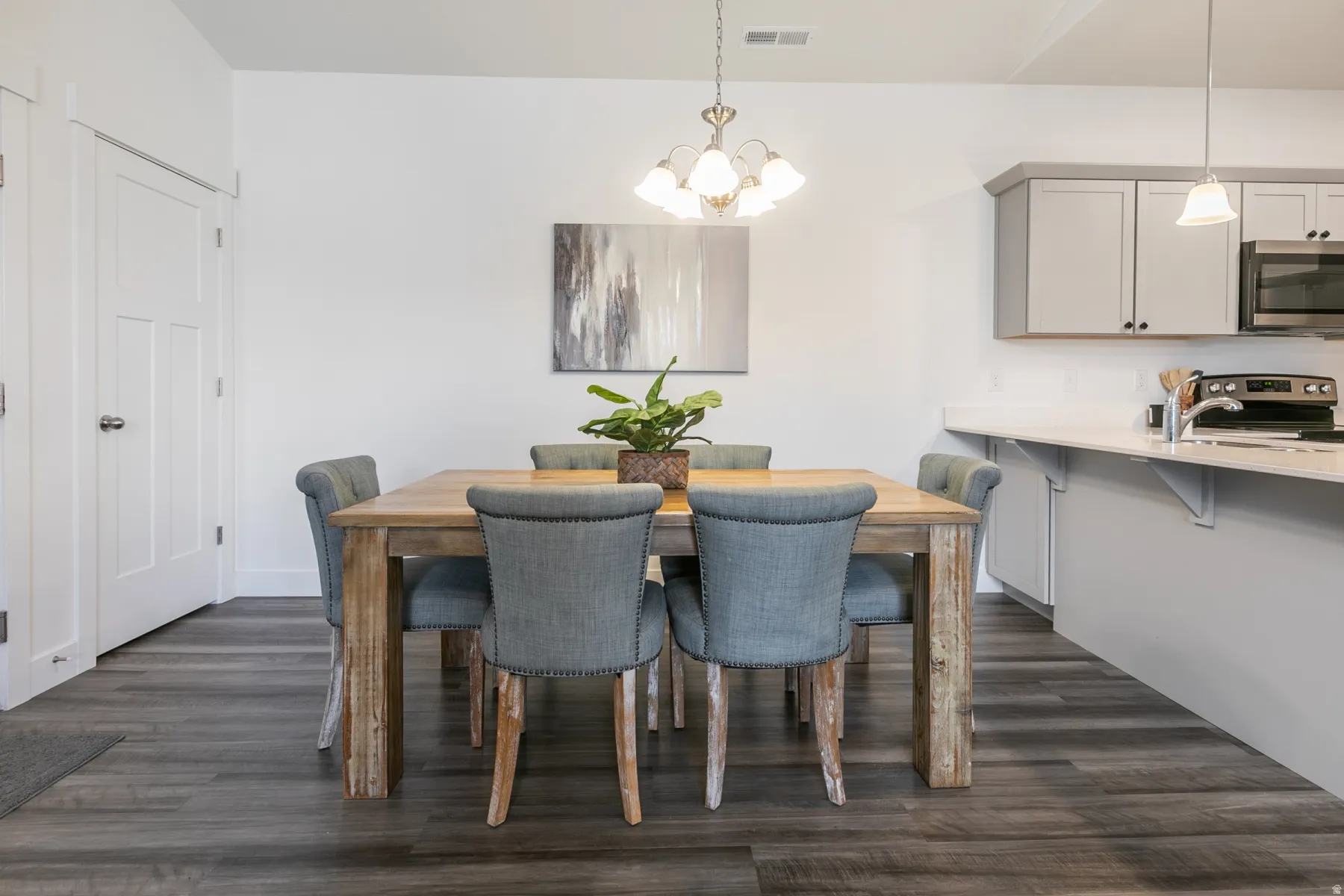 Dining area featuring wood-finish flooring, a contemporary chandelier, and white paneled doors