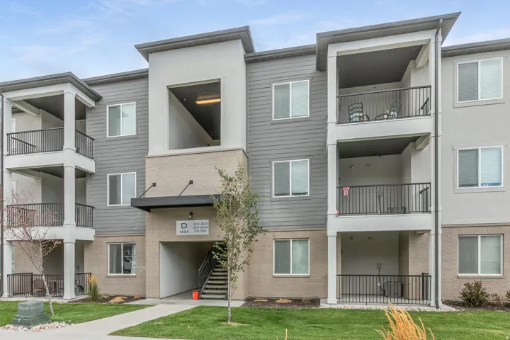 Contemporary multi-story building featuring gray siding, light-colored stucco, and brick facade elements
