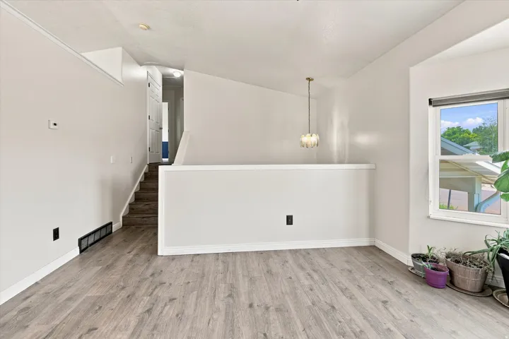 Spacious living area featuring wood-finish flooring, a contemporary chandelier, and a large window
