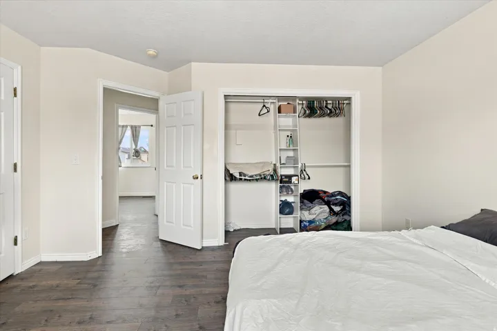 Bedroom featuring wood-finish flooring, a bi-fold closet with built-in shelving, and white interior doors