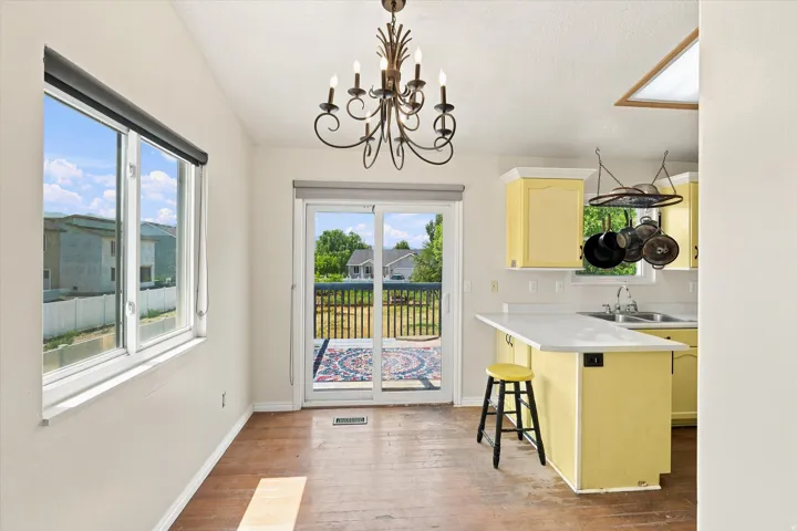 Open-concept dining area with wood-finish flooring, featuring a decorative chandelier and a large picture window