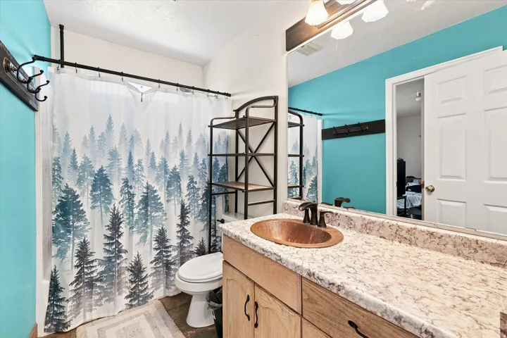 Bathroom featuring a vanity with a copper basin sink, a patterned countertop, and light wood-finish cabinetry